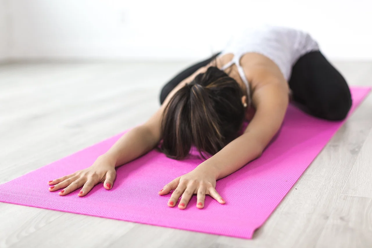 Vrouw in de kindhouding op een roze yogamat