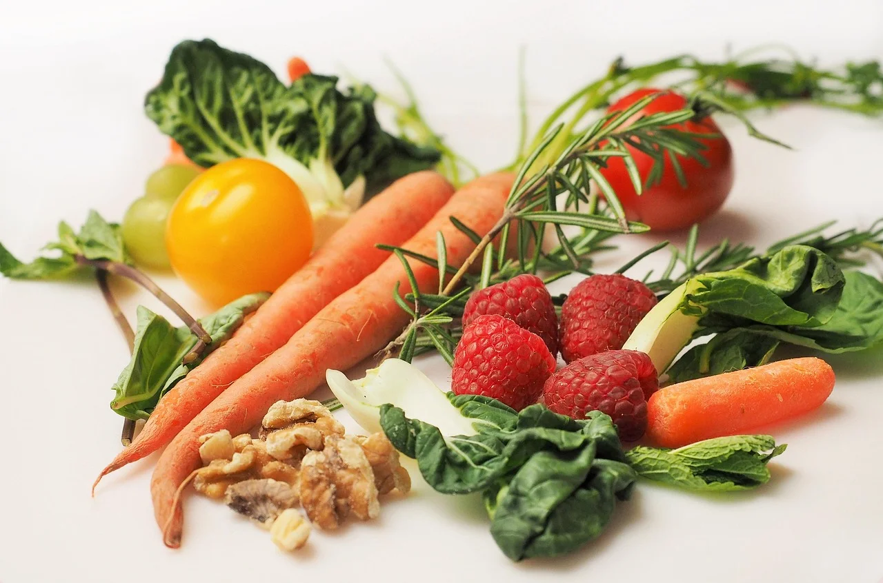 Verse wortels, tomaten, frambozen, spinazie en walnoten op een witte ondergrond